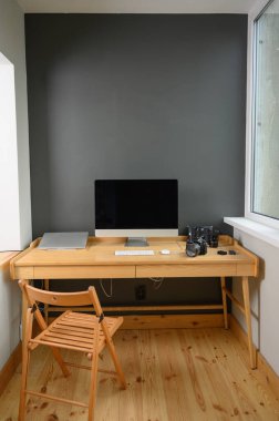 Profesyonel kamera ve bilgisayarlı fotoğrafçı işyeri. Ahşap masa üzerinde bilgisayar, dizüstü bilgisayar ve kamera olan işyeri.