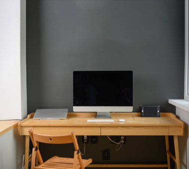 Profesyonel kamera ve bilgisayarlı fotoğrafçı işyeri. Ahşap masa üzerinde bilgisayar, dizüstü bilgisayar ve kamera olan işyeri.