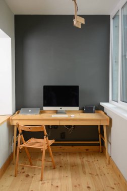 Profesyonel kamera ve bilgisayarlı fotoğrafçı işyeri. Ahşap masa üzerinde bilgisayar, dizüstü bilgisayar ve kamera olan işyeri.