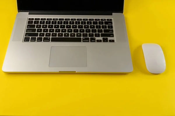 Top view of laptop and mouse on yellow background.Flat lay composition with notebook and mouse on yellow background