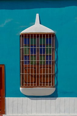 Renkli bir duvarda parmaklıkları olan antik bir pencere