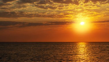 Ufukta güzel kırmızı günbatımı, koyu bulutlar ve okyanus