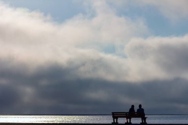iki kişi bir sokak bankta oturan ve dramatik günbatımı izliyor 