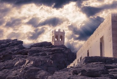 dramatik bir bulutlu gökyüzü altında bir kaya üzerinde terk edilmiş eski taş küçük kule