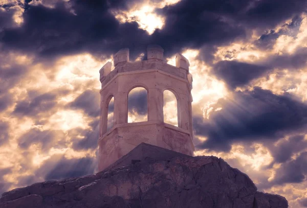 dramatik bir bulutlu gökyüzü altında bir kaya üzerinde terk edilmiş eski taş küçük kule