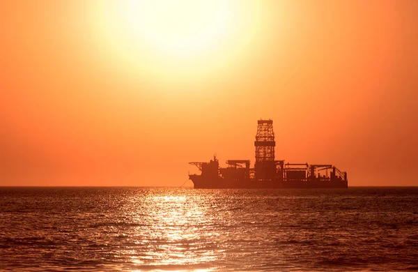 A large vessel on horizon in the atlantic ocean under the bright sun and red sunset.  Sunlight reflection off the water