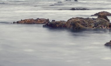 Namibya, Afrika'da Atlas Okyanusu'nda gün batımında kaya oluşumunu çevreleyen suyu çevreleyen yavaş deklanşör hızı