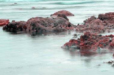 Namibya, Afrika'da Atlas Okyanusu'nda gün batımında kaya oluşumunu çevreleyen suyu çevreleyen yavaş deklanşör hızı