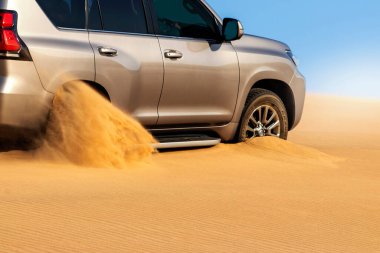Namib çölünde kumda sıkışmış altın bir arabanın yakınında. Afrika