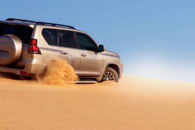 Namib çölünde kumda sıkışmış altın bir arabanın yakınında. Afrika