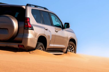 Namib çölünde kumda sıkışmış altın bir arabanın yakınında. Afrika