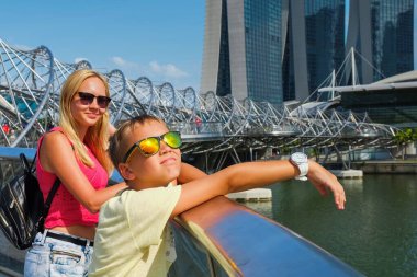 Singapur 'a seyahat, Geleceğin Şehri. Bir çift Kafkasyalı çocuk gezgini, erkek ve kız kardeş, günlük giysiler içinde aile gezisinde birlikte eğleniyorlar. Helix Köprüsü, Singapur.