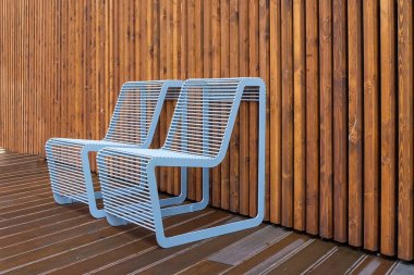 Yağmurlu bir günde konut alanının avlusunda dinlenme yeri. Islak ahşap kalkanların arka planına yakın modern tasarım yağmur damlaları olan iki ıslak metal sandalye. Rahat kentsel mobilyalar..