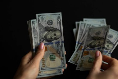 Eller siyah arka plan ile 100 dolar para faturaları saymak