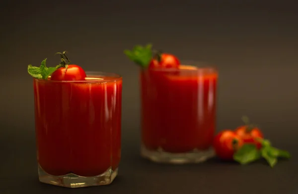 黒い背景を持つチェリートマトとミントのトマトジュース2杯 — ストック写真