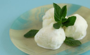 Mavi arka planlı mavi bej plaka üzerinde nane ile üç vanilyalı dondurma topları yakın çekim