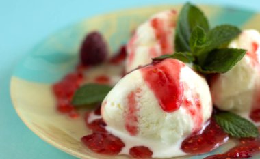 Mavi arka planlı mavi bej plaka üzerinde ahududu reçeli ve nane ile üç vanilyalı dondurma topları yakın çekim