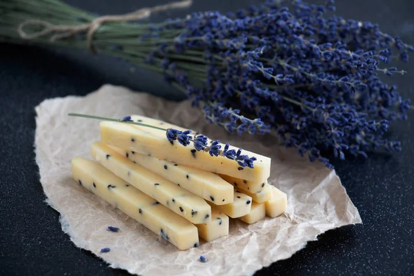 Koyu bir arka plan ile parşömen kağıt üzerinde lavanta sprigs ile lavanta peyniri Dilimleri