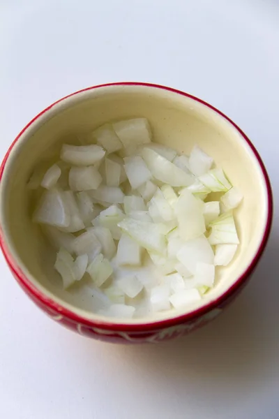 Kırmızı bir kapta yemek pişirmek için doğranmış soğan