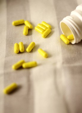 Gri ve beyaz çizgili kumaş üzerine sarı vitaminler