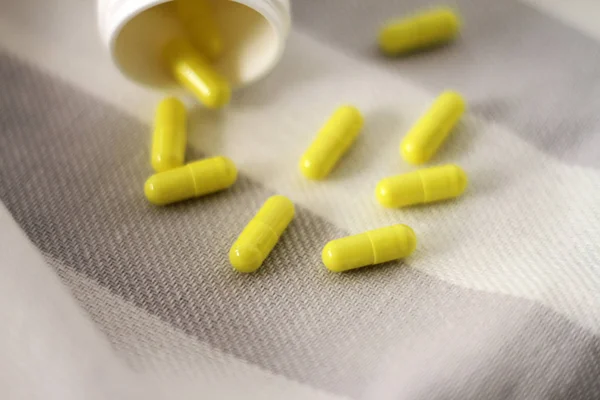 Gri ve beyaz çizgili kumaş üzerine sarı vitaminler