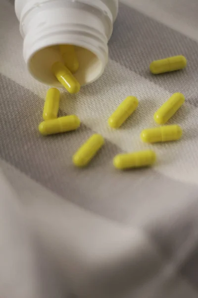 Gri ve beyaz çizgili kumaş üzerine sarı vitaminler