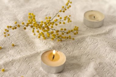 Beyaz dokulu arka plan beyaz sarı çiçekler üzerinde küçük mum