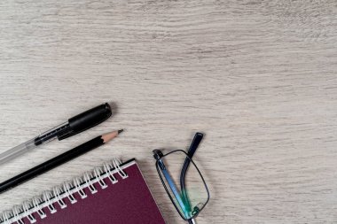 Ahşap gri arka plan üzerinde not defteri, kalem, kalem ve gözlük