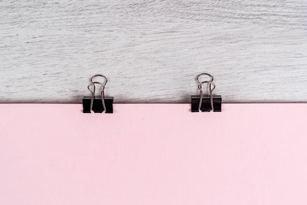 Binder clip holds a pink sheet of paper