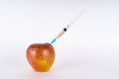 Şırıngayla kırmızı elma enjeksiyonu. Antibiyotik ya da Gdo. Beyaz arka planda genetiği değiştirilmiş meyve