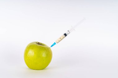 Şırıngayla yeşil elma enjeksiyonu. Antibiyotik ya da Gdo. Beyaz arka planda genetiği değiştirilmiş meyve