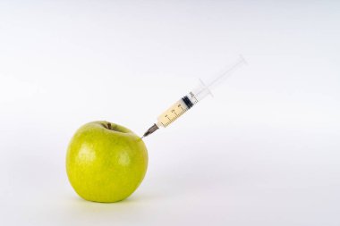 Şırıngayla yeşil elma enjeksiyonu. Antibiyotik ya da Gdo. Beyaz arka planda genetiği değiştirilmiş meyve