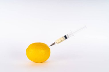 Şırıngayla limon enjeksiyonu. Antibiyotik ya da Gdo. Beyaz arka planda genetiği değiştirilmiş meyve