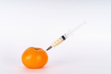 Şırıngayla mandarin enjeksiyonu. Antibiyotik ya da Gdo. Beyaz arka planda genetiği değiştirilmiş meyveler