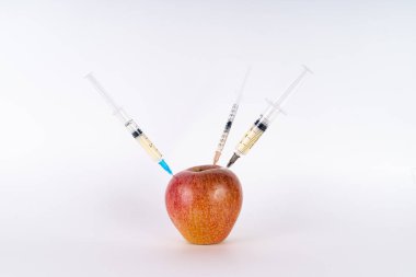 Üç şırıngalı kırmızı elma enjeksiyonu. Antibiyotik ya da Gdo. Beyaz arka planda genetiği değiştirilmiş meyveler
