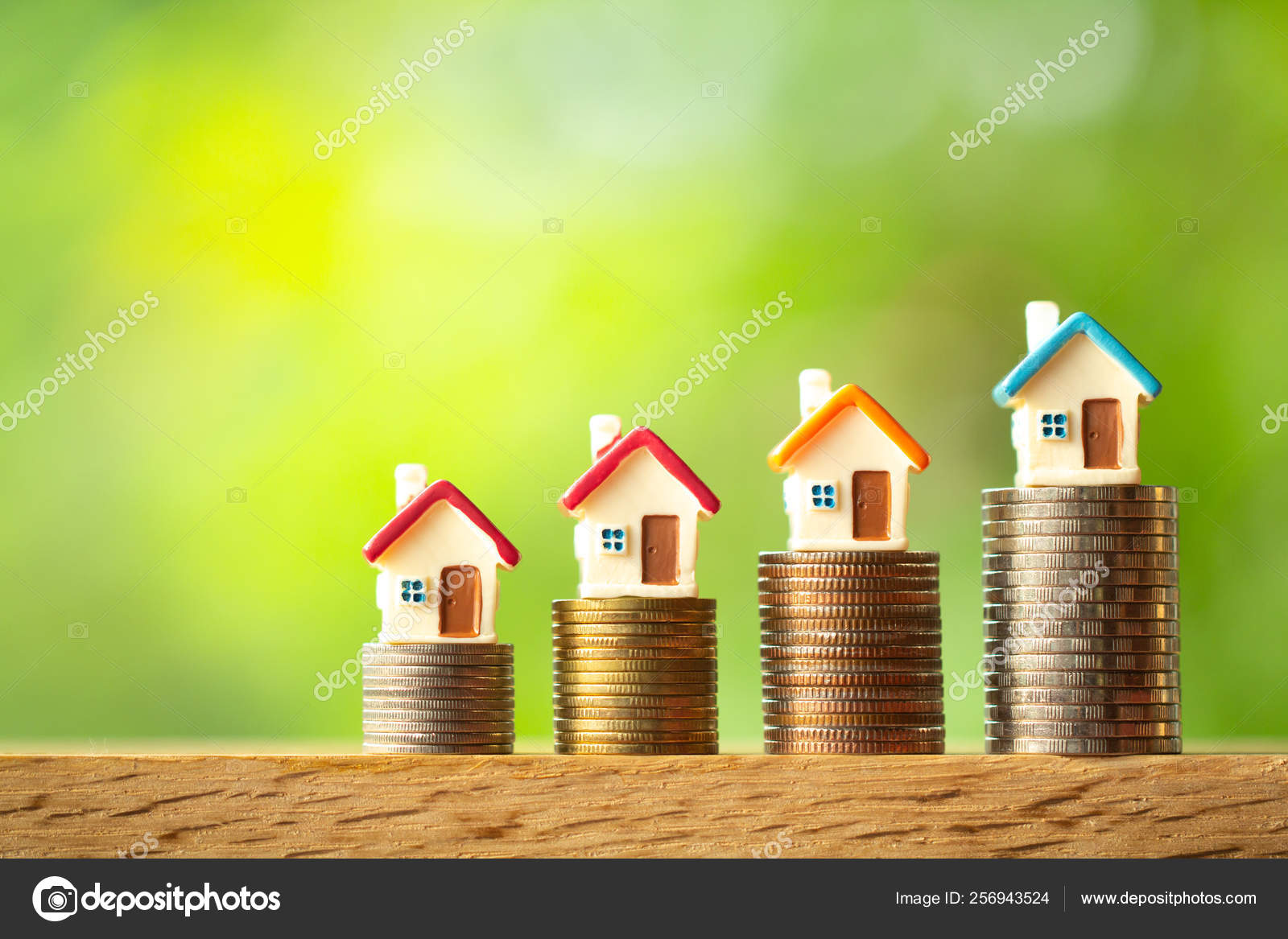 Four miniature house models on coin stacks on greenery blurred b Stock  Photo by ©thecop_nn 256943524