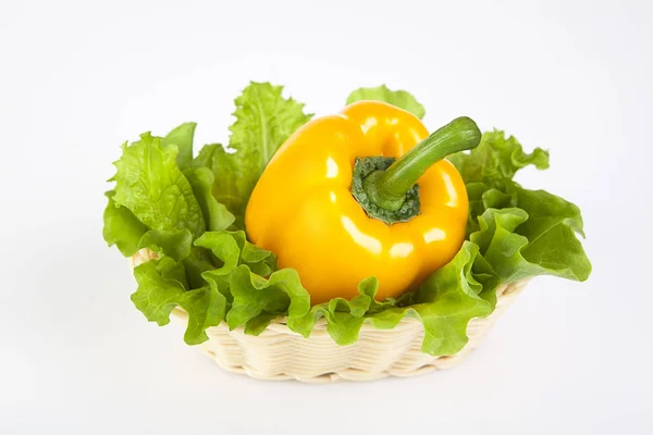 yellow pepper with green salad in a basket on a gray background
