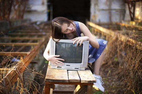 古い放棄された家でレトロなアナログテレビを抱きしめる若い笑顔の女性のヴィンテージアートの肖像画 — ストック写真