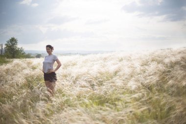 Seksi genç mutlu kadın alanında duran ve gün batımı zevk