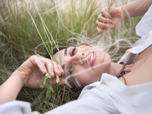草の上に横になって休息を楽しんでいる若い美しい女性 — ストック写真
