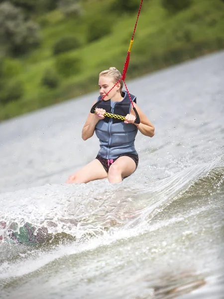 woman makes an extreme jump on wakeboarding, around there are a lot of splashes water. This is an extreme sport.