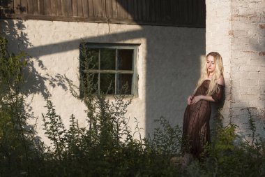 güzel kadın eski bir terk edilmiş evin arka plan üzerinde bir taş duvar yakınında duruyor