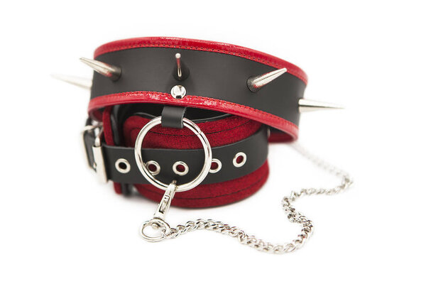 Leather handcuffs and collar with spikes connected by a chain isolated on white background.