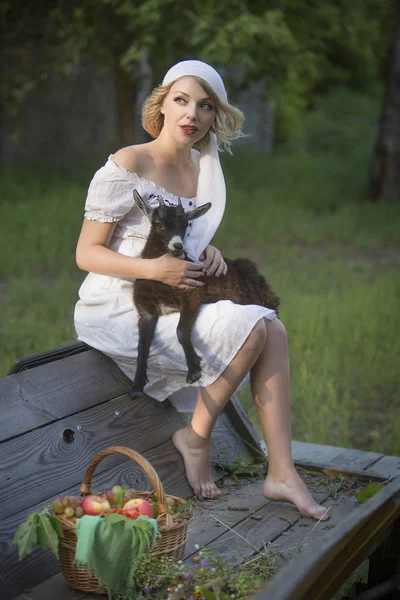 kollarında küçük bir keçi tutan güzel genç kadın