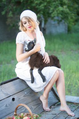 Güzel genç bir kadın küçük bir keçiyi besler. Kırsal yaşam