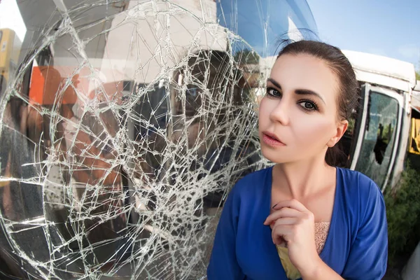 frightened woman by the broken glass of a car