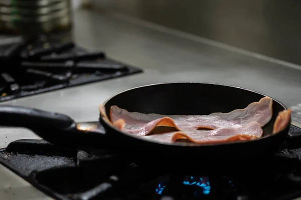 Bacon strips cooked in frying pan.