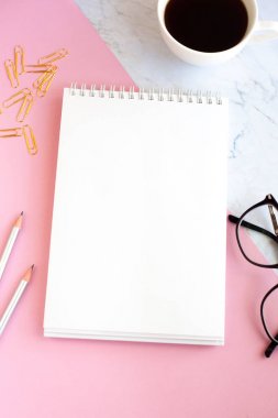 İş Işyeri kahve, defter, kalem ve altın kağıt klipler, gözlük bir fincan ile minimalist bir tarzda. Pembe ve mermer arka plan