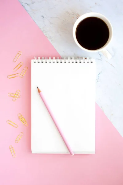 İş Işyeri kahve, defter, kalem ve altın kağıt klipleri bir fincan ile minimalist bir tarzda. Pembe ve mermer arka plan