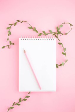 Defter, beyaz çarşaf, kalem, çiçekler. Pembe arka plan